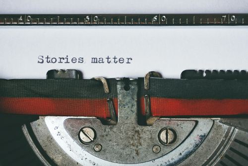 Close-up of a vintage typewriter with the text 'Stories matter' typed on paper, evoking nostalgia.