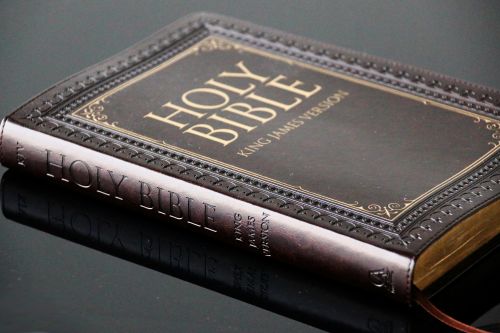 Close-up view of a leather bound King James Version Holy Bible resting on a reflective surface.